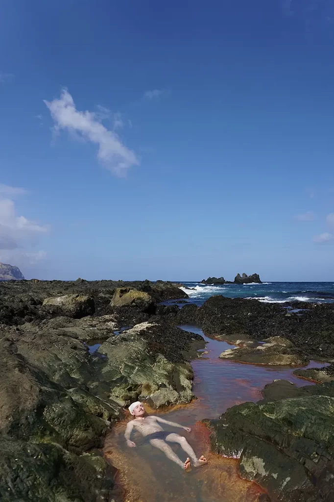 Hiking man bathes in Adak mountain spring.
